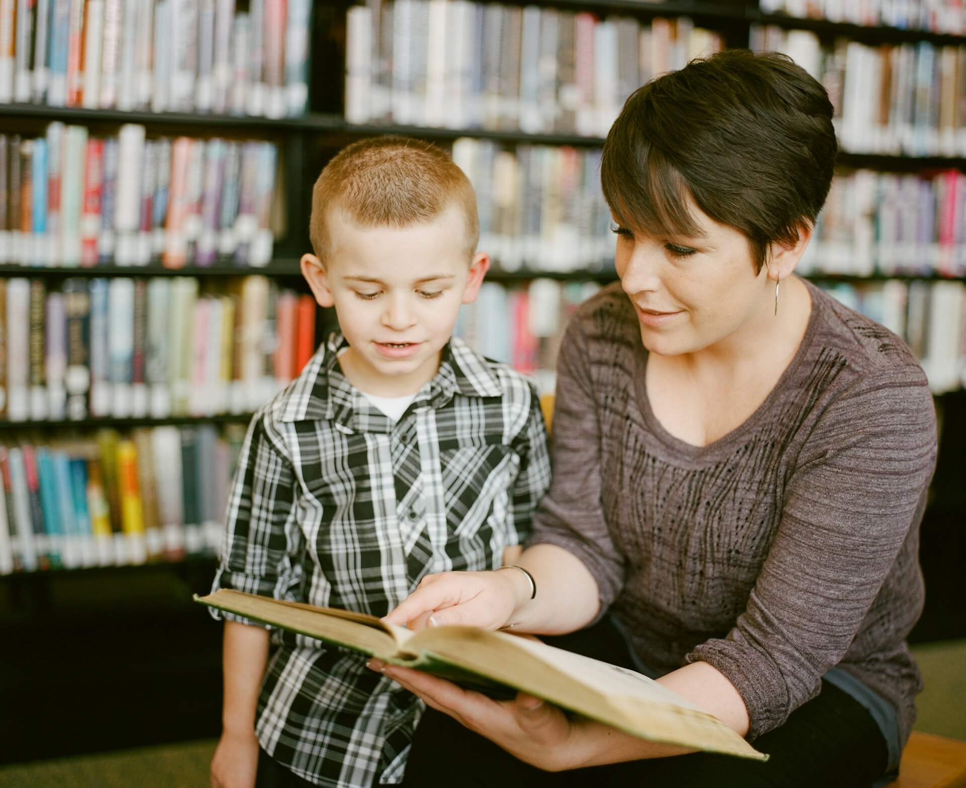 speech-language pathologist opens the book for a child