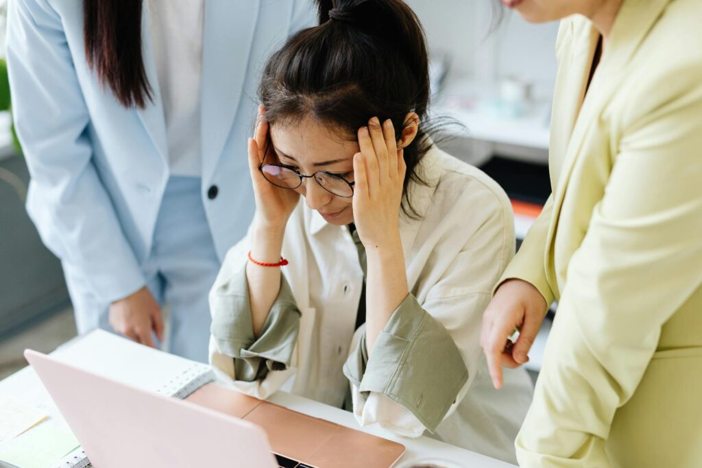 Woman holding her head looking at computer