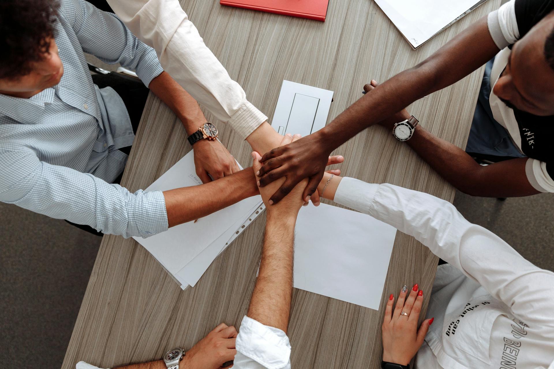 Group of businesspeople around table putting hands in