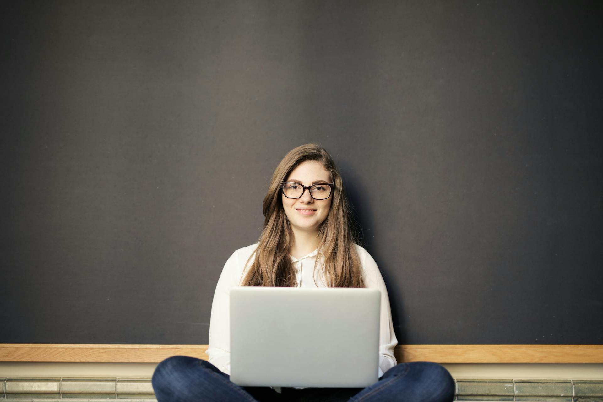 Woman holding laptop sitting on ground