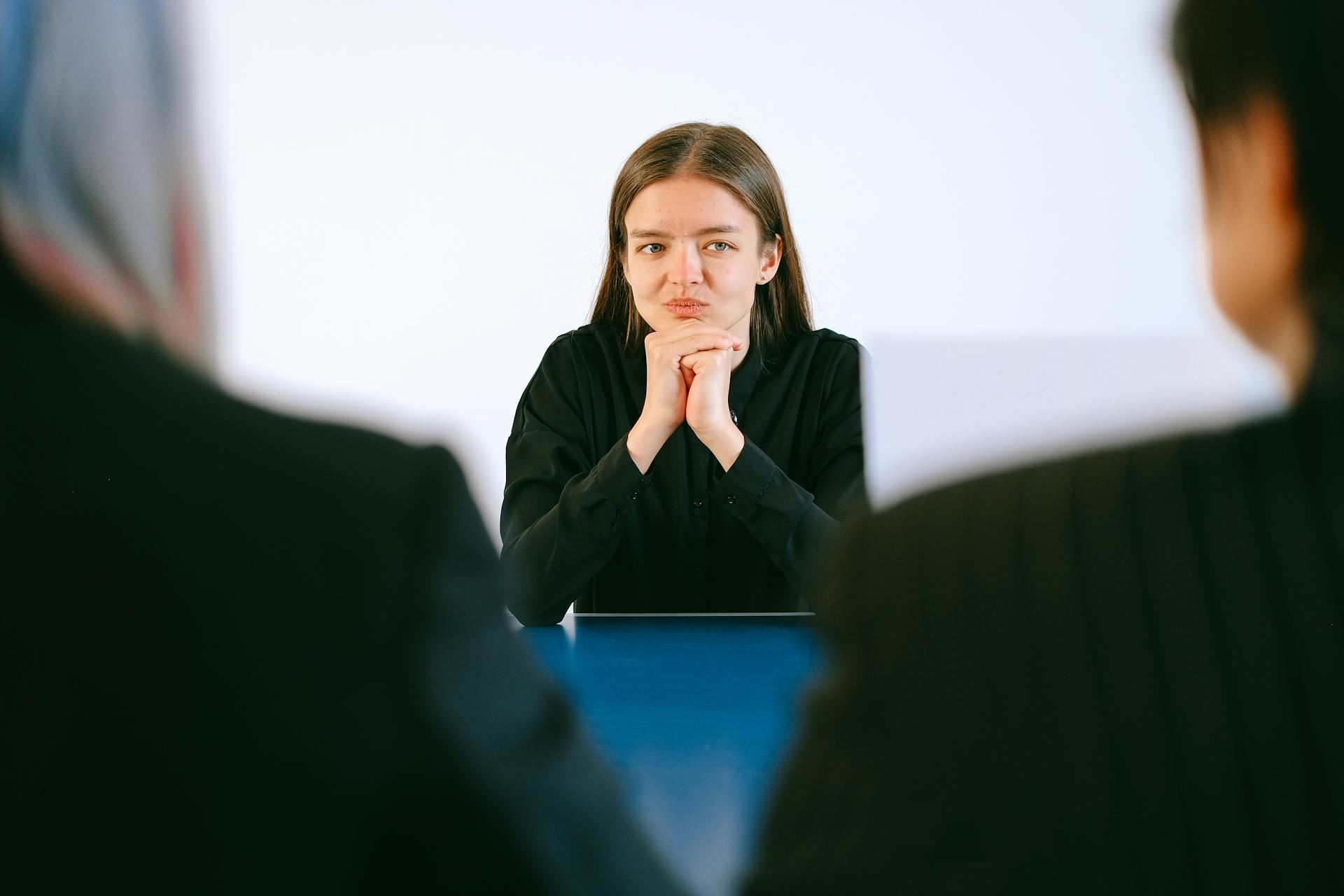 A young woman sits across a table from two interviewers